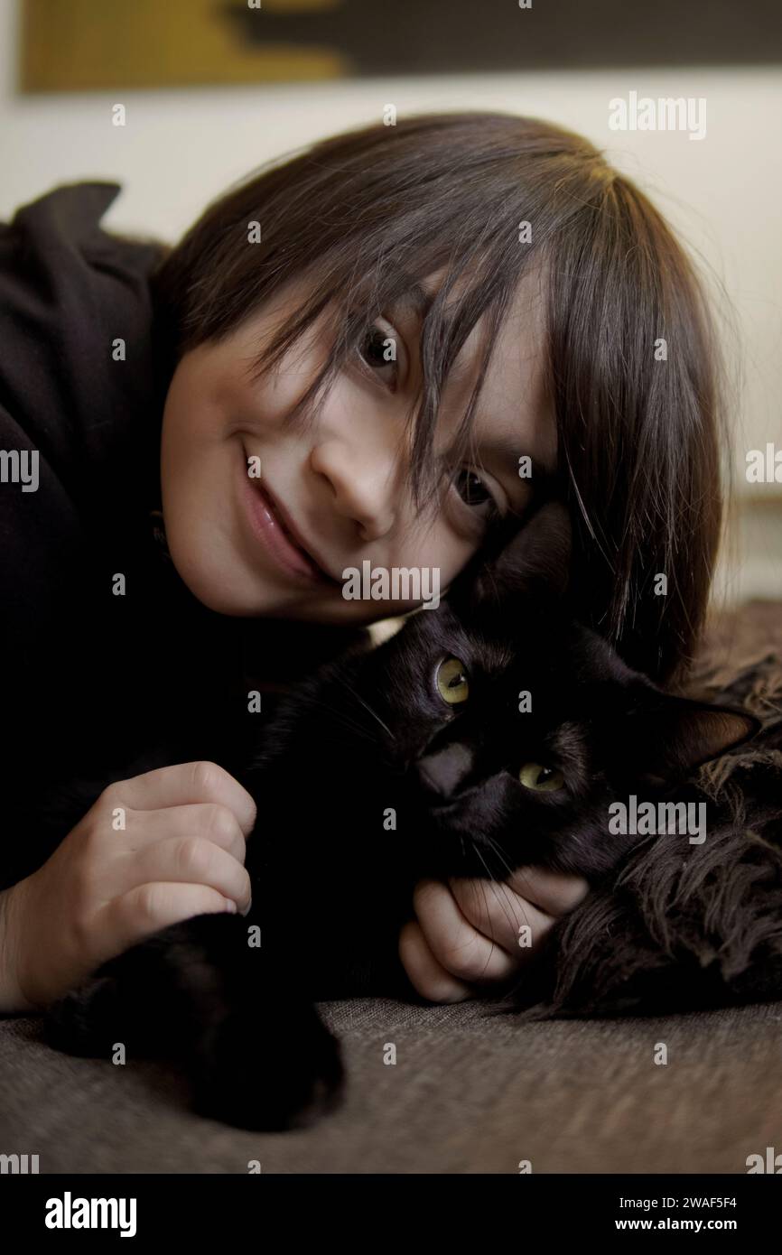 Hispanic boy smiling hugging his black cat Stock Photo