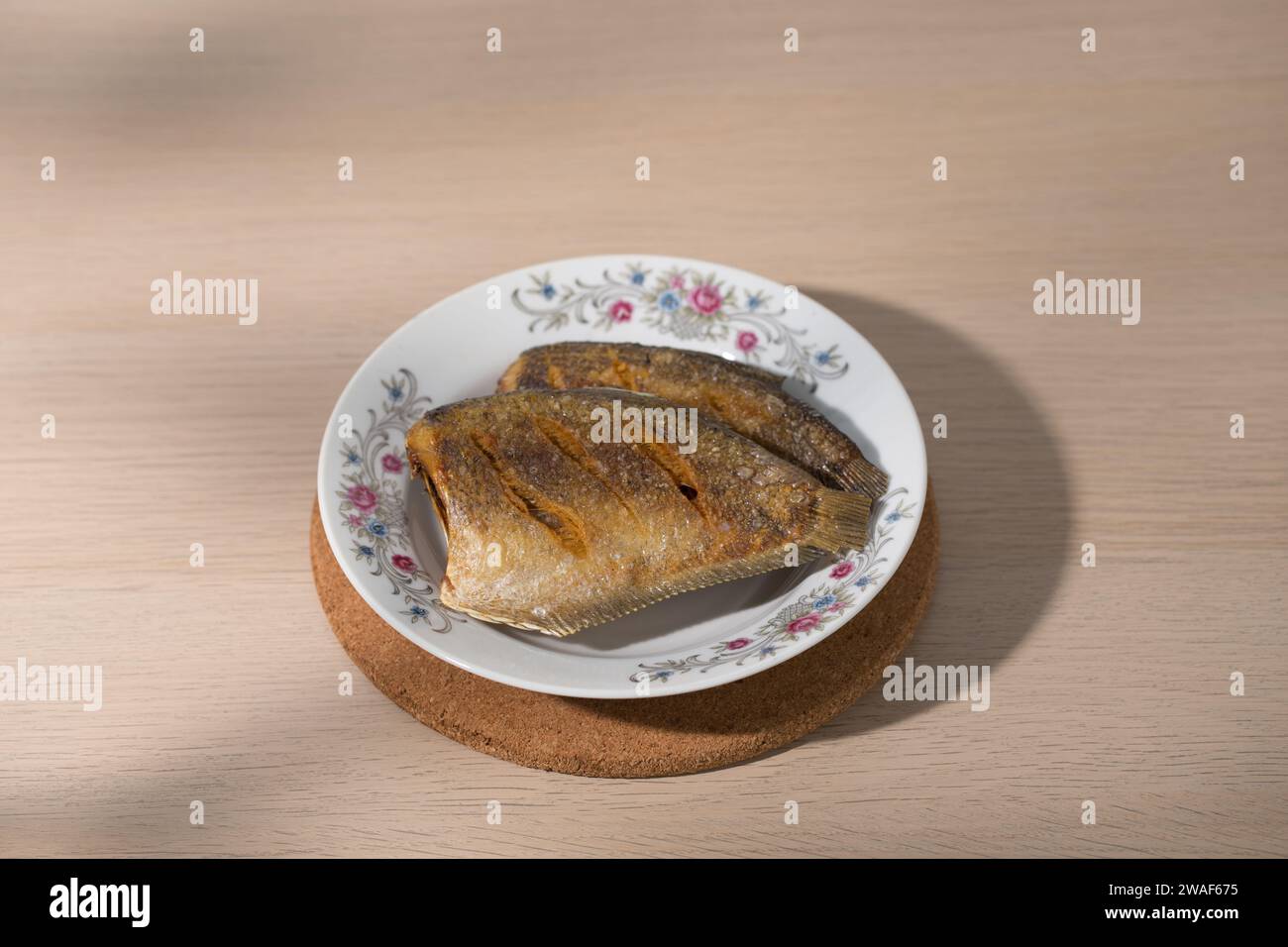 Bang Khae, Bangkok  Thailand - January 04 2024: Fried gourami fish with Thai-style rice on a white plate with flower pattern. Stock Photo