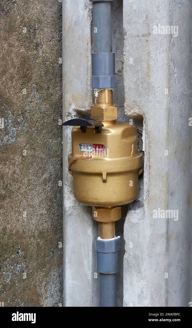 closeup of installed outdoor household water meter, gold colored