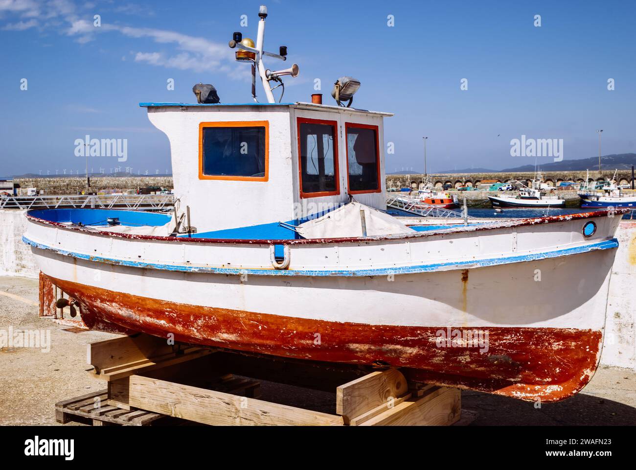 A small fishing boat on a wooden stand in a harbor Stock Photo