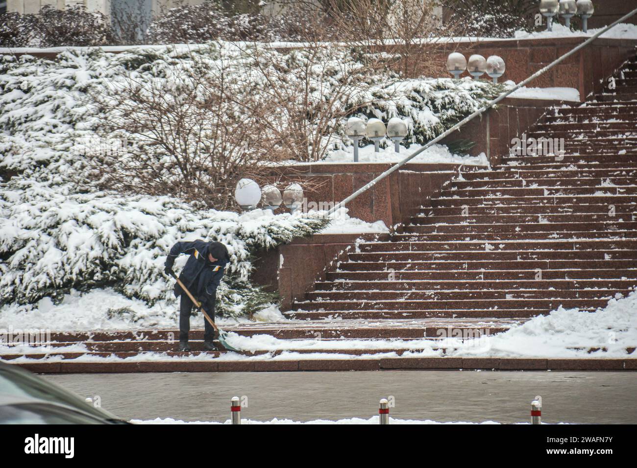 Non Exclusive KYIV UKRAINE JANUARY 4 2024 A Man Spades Away Snow   Non Exclusive Kyiv Ukraine January 4 2024 A Man Spades Away Snow From The Steps In Winter Kyiv Capital Of Ukraine 2WAFN7Y 