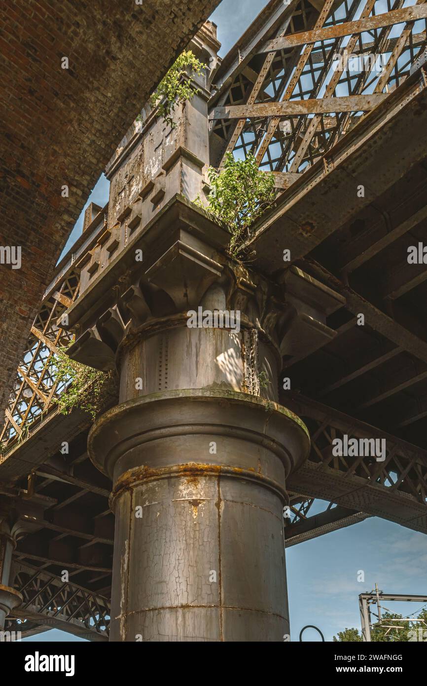 Detail of a steel rail bridge supported by a large metal pillar. Concept of strength, connectivity, support or travel. Stock Photo