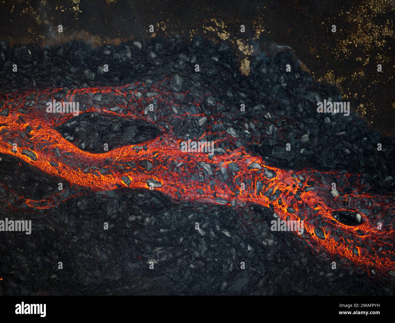Mesmerizing view of a lava flow, red hot molten liquid streaming over