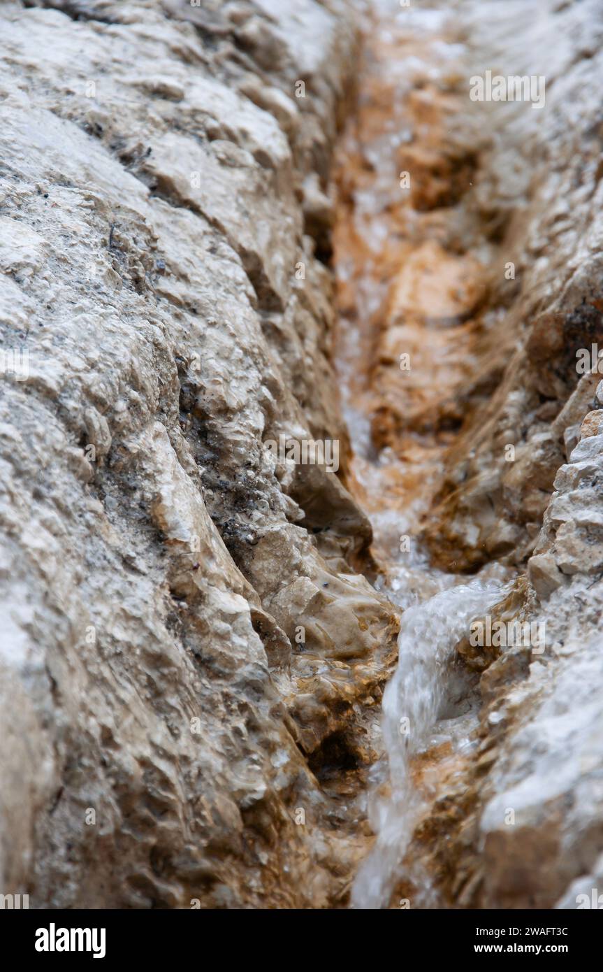 Small stream flows between brown ferruginous limestone rocks. Motion ...