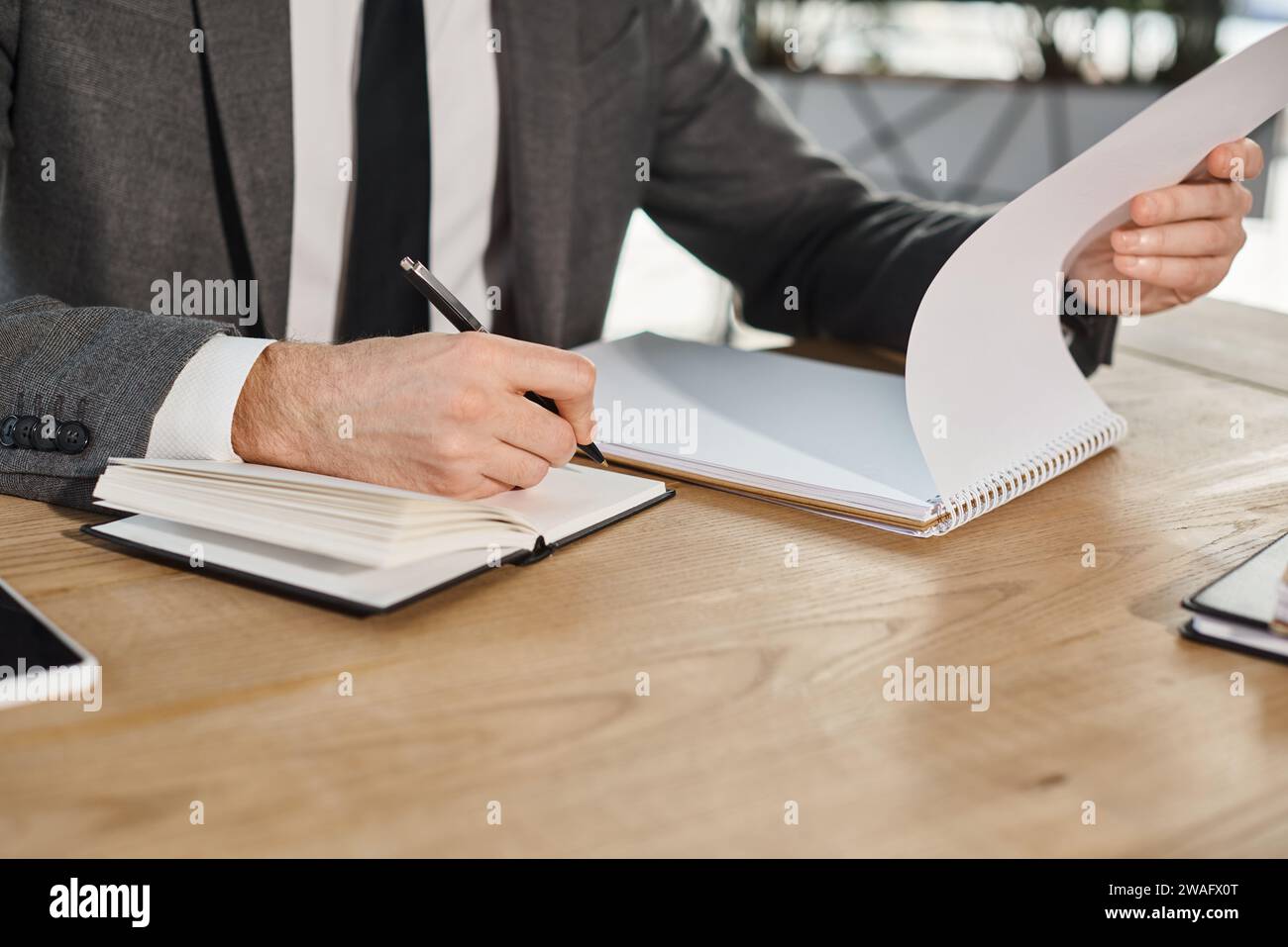 cropped view of businessman writing in notebook on work desk in modern office, busy lifestyle Stock Photo