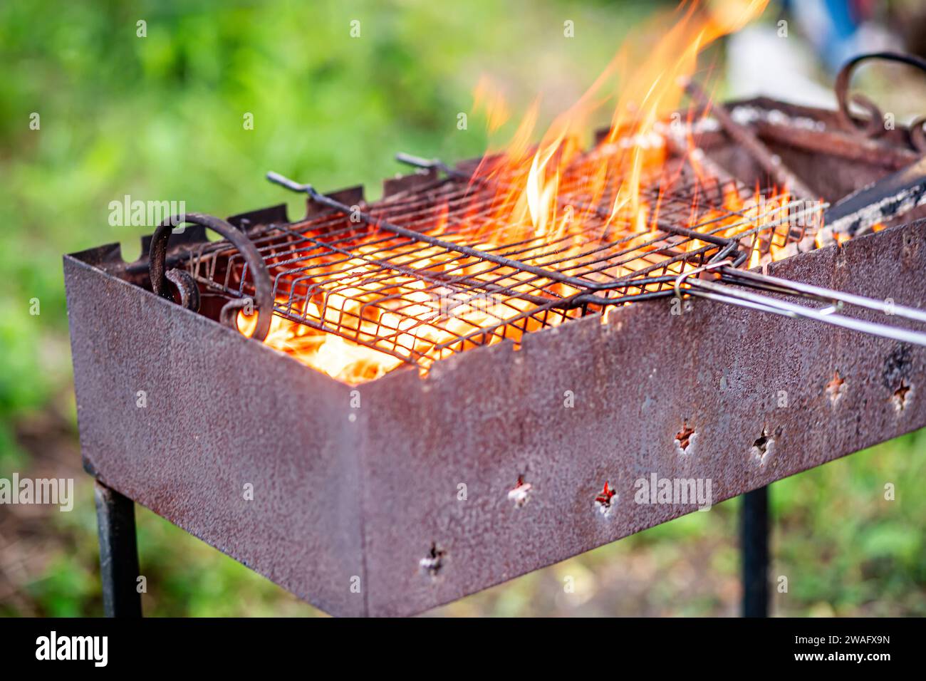 A large metal grill filled with burning wood and an old rusty grill