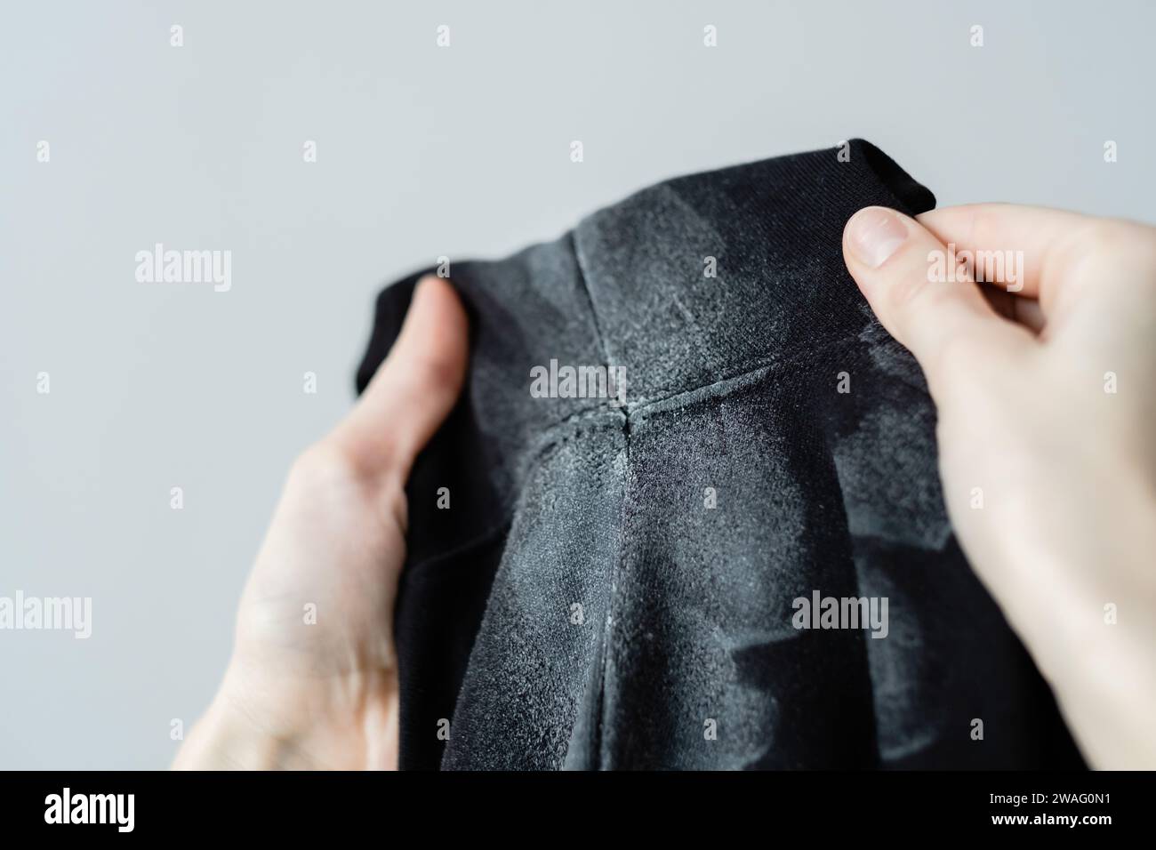 A woman's hand is showing white marks on deodorant stains in black clothes. Spoiled clothes. daily life stain concept. Stock Photo