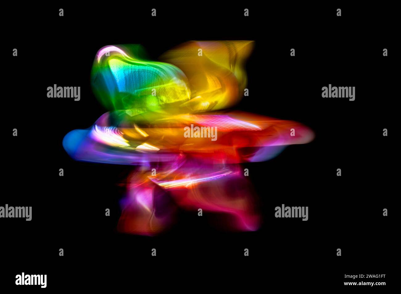 A front view of a regular toy pinwheel windmills with six differently psychedelic colored vanes rotating on a stick on a black screen background, slow Stock Photo