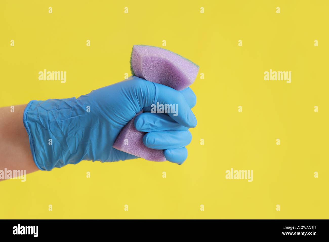 Hand and sponge for washing dishes. Hand in a blue glove with a sponge ...