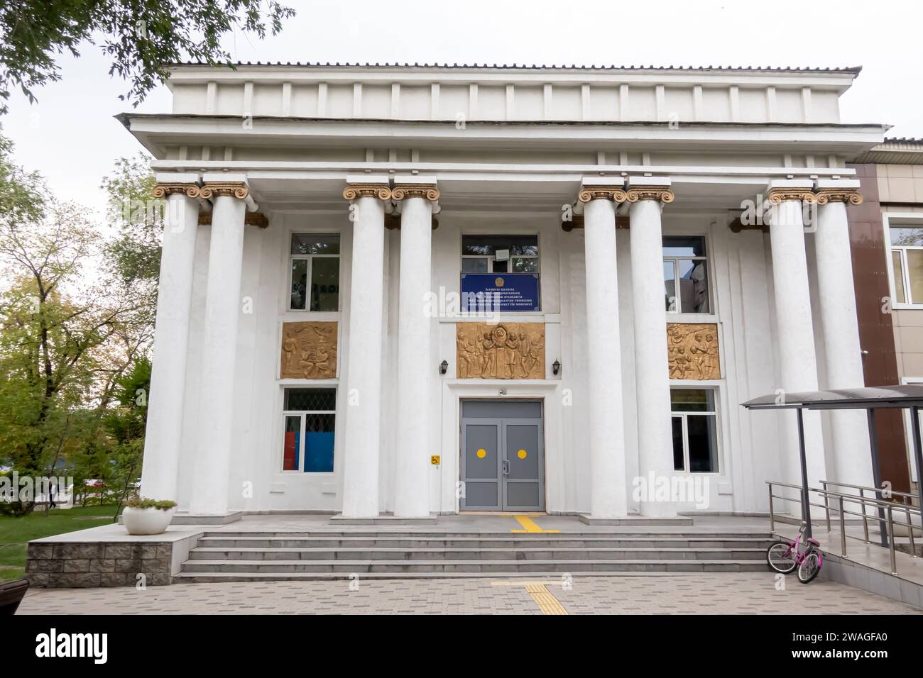 Gymnasium #56 building, eclectic architecture, classicism, neo-classicism, Almaty Kazakhstan. Bas reliefs by  Artist Ivan Vakhek. 1936 Stock Photo