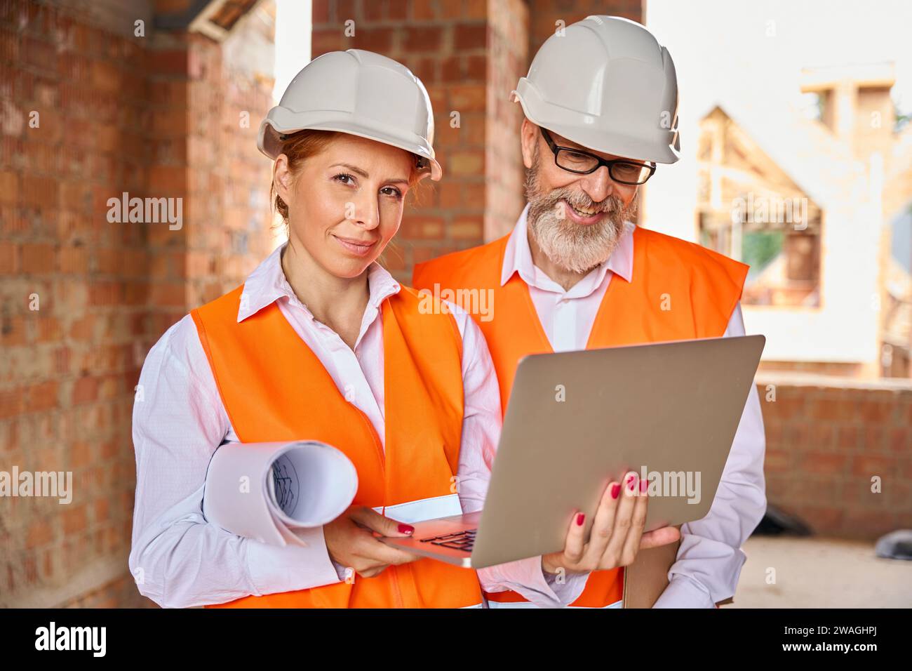 Construction professionals using portable computer in unfinished dwelling house Stock Photo
