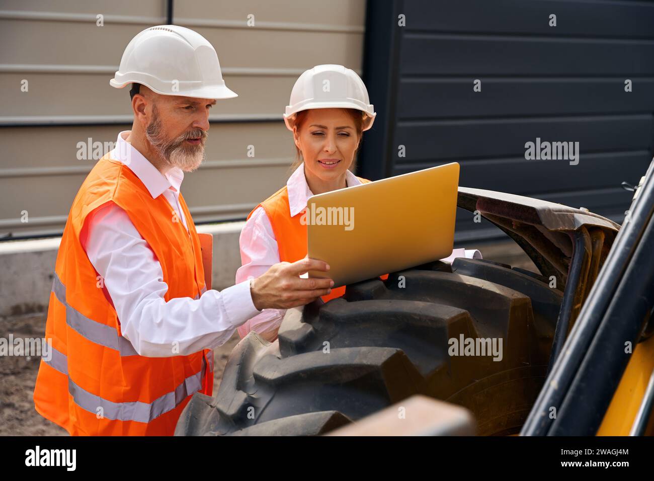Team of construction specialists using together computer during site inspection Stock Photo
