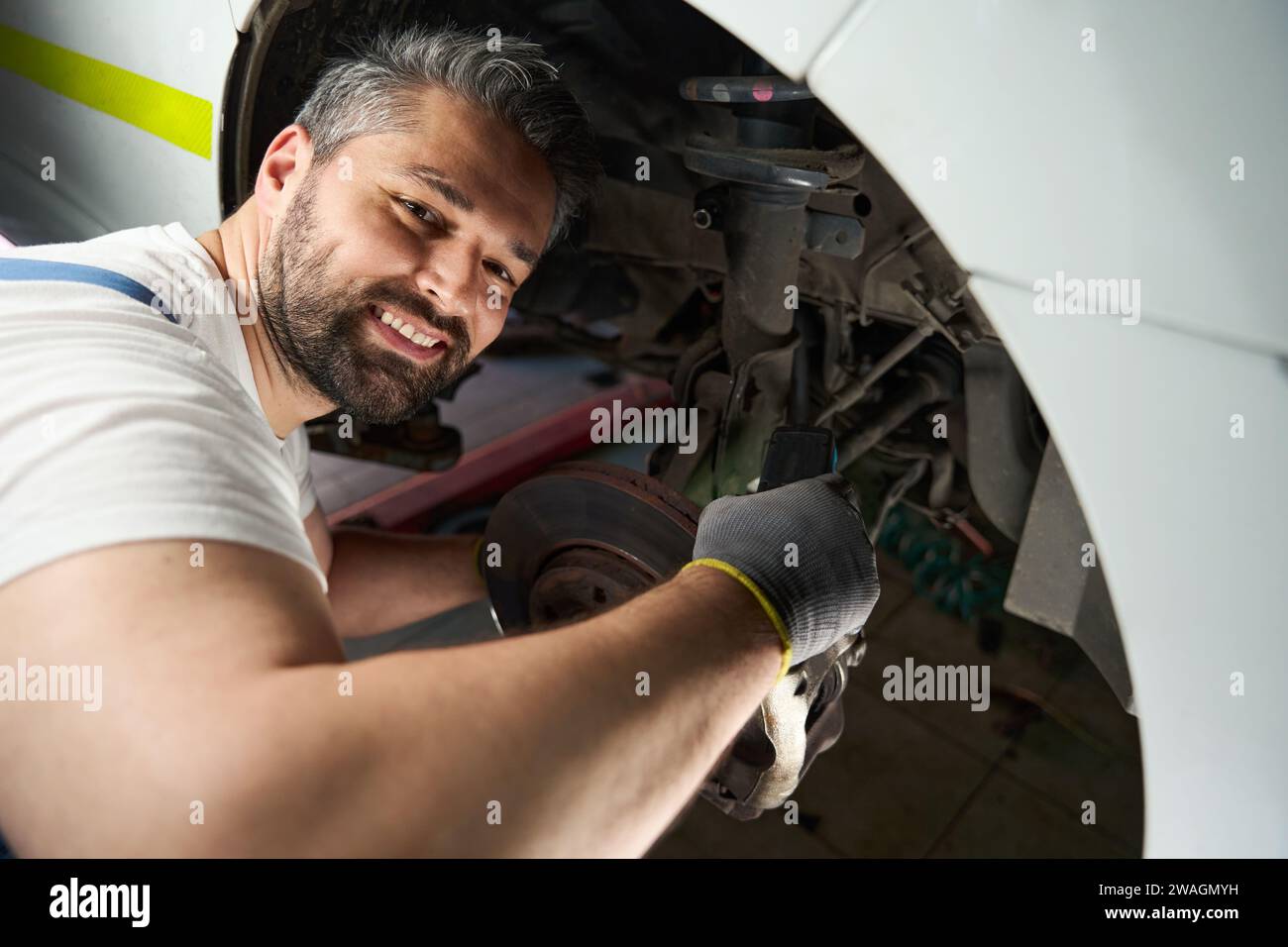 Cheerful vehicle mechanic checking client car with digital device Stock Photo