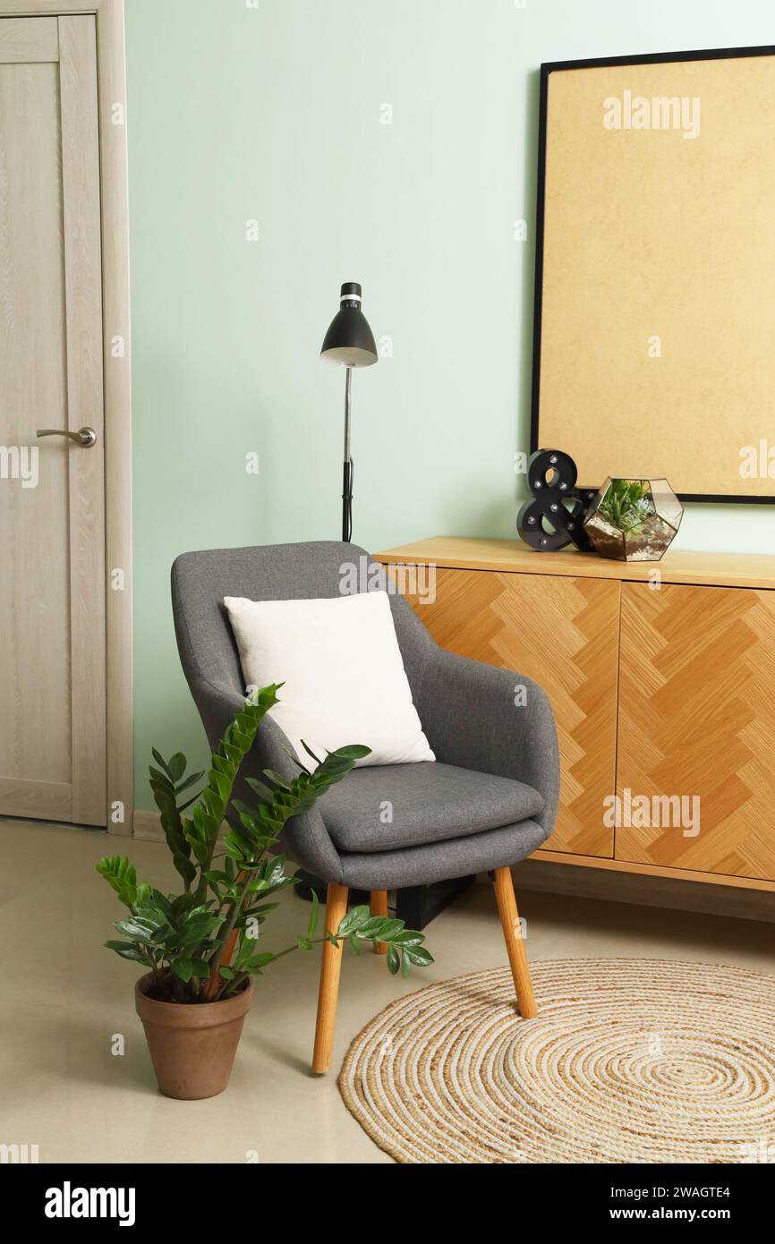 Interior of living room with armchair, drawers and lamp Stock Photo - Alamy