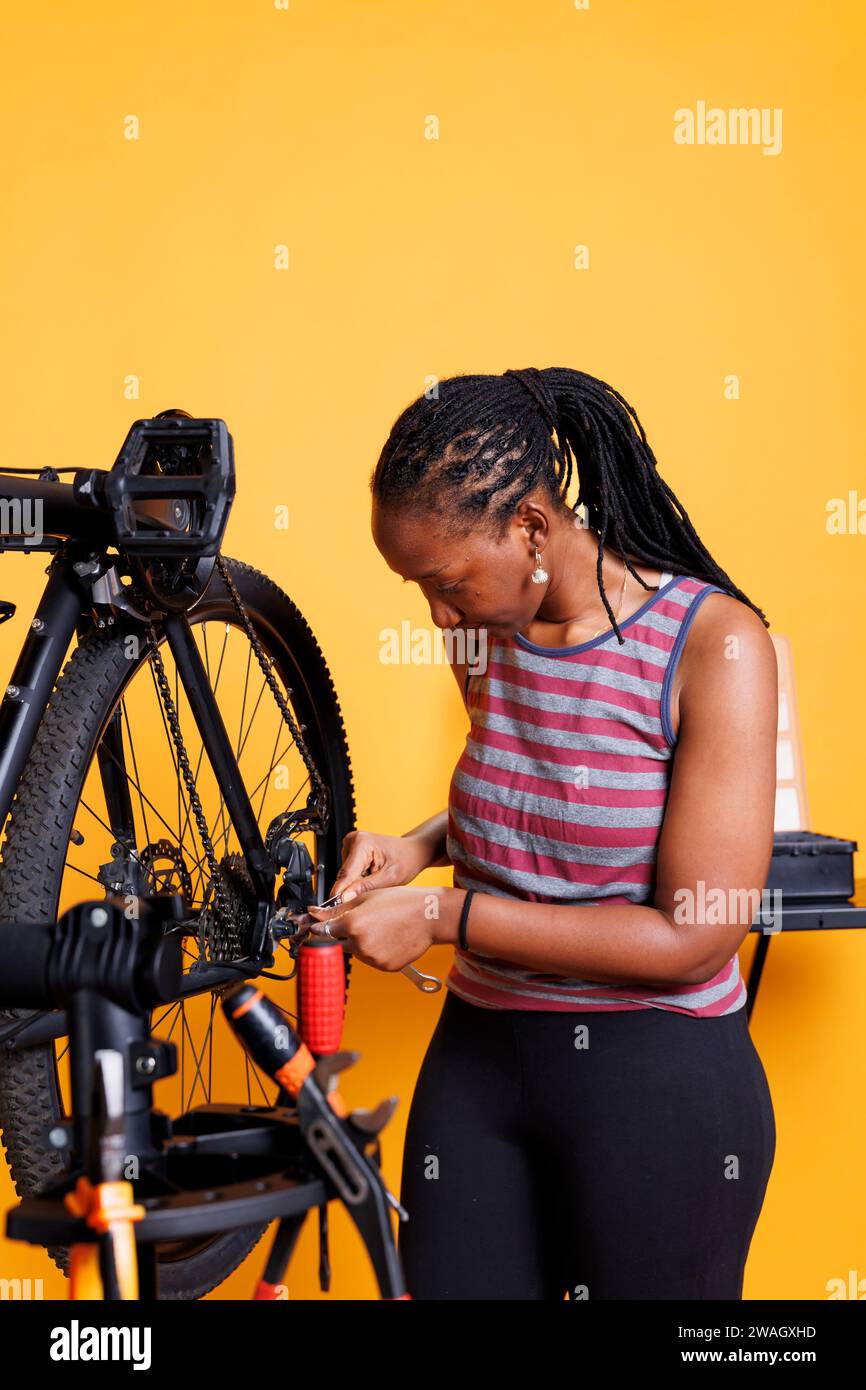 African american female cyclist adjusts and repairs bicycle components with specialized toolkit