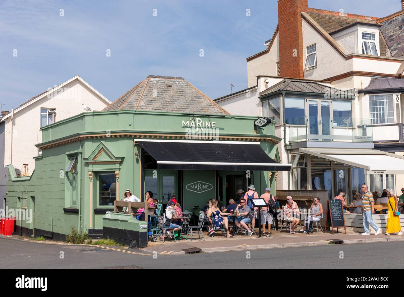Sidmouth esplanade Devon England, hot day in September 2023 and people enjoy a drink at the Marine pub bar in Sidmouth Town centre,England,UK Stock Photo