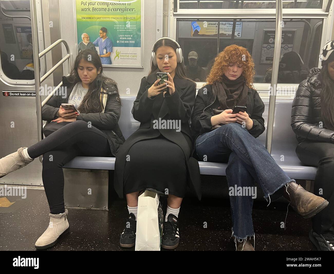 Subway riders on their cell phones as they ride along in New York City. Stock Photo