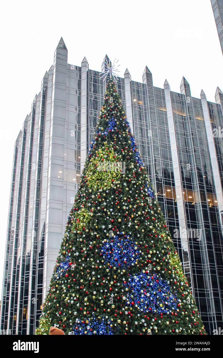 The Christmas tree in the center of PPG Arena ice skating rink is lit with the Pittsburgh Plate Glass Skyscraper in the background Stock Photo