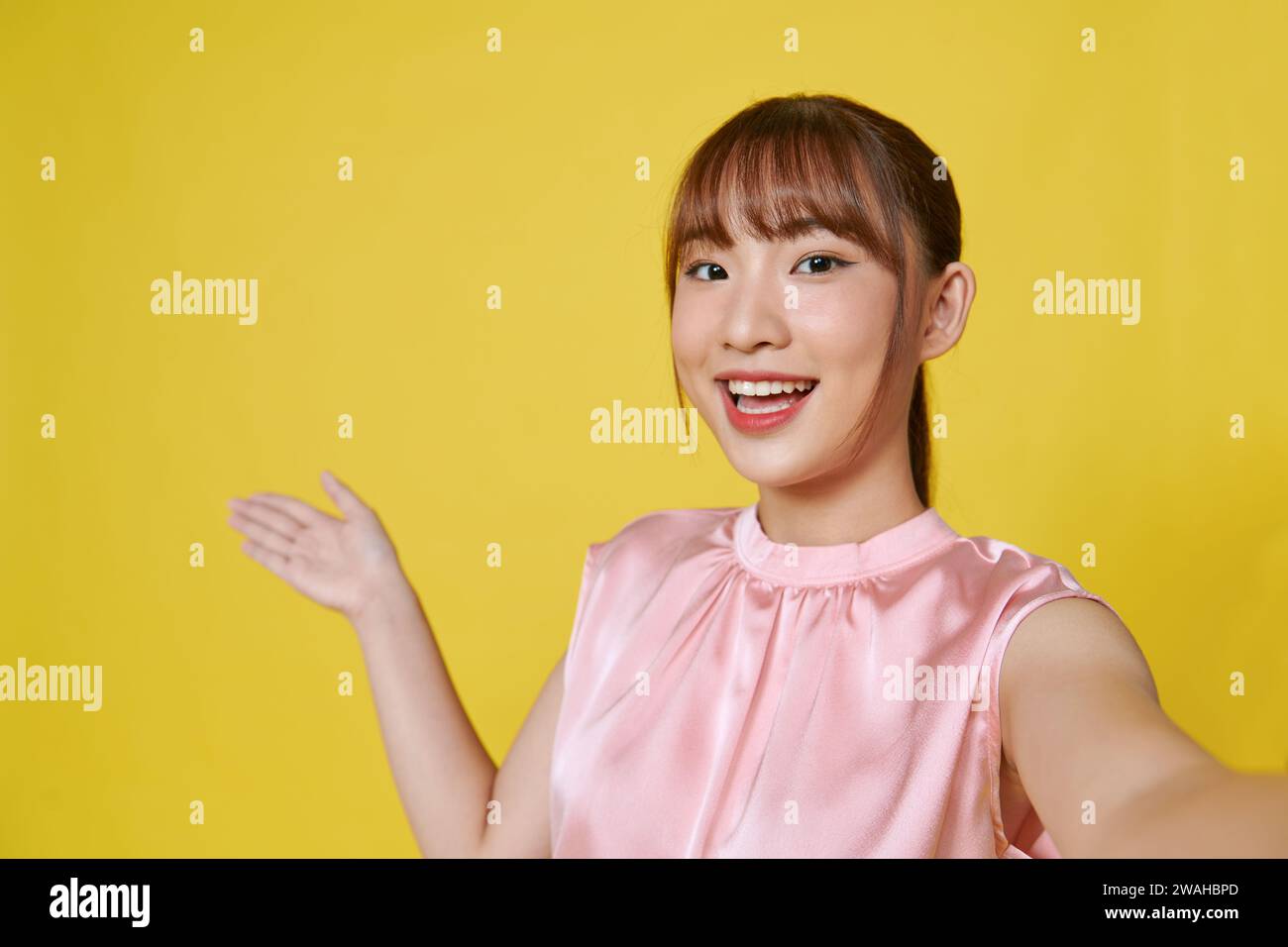 Beautiful woman make selfie by camera, pointing aside with hands open palms showing copy space Stock Photo