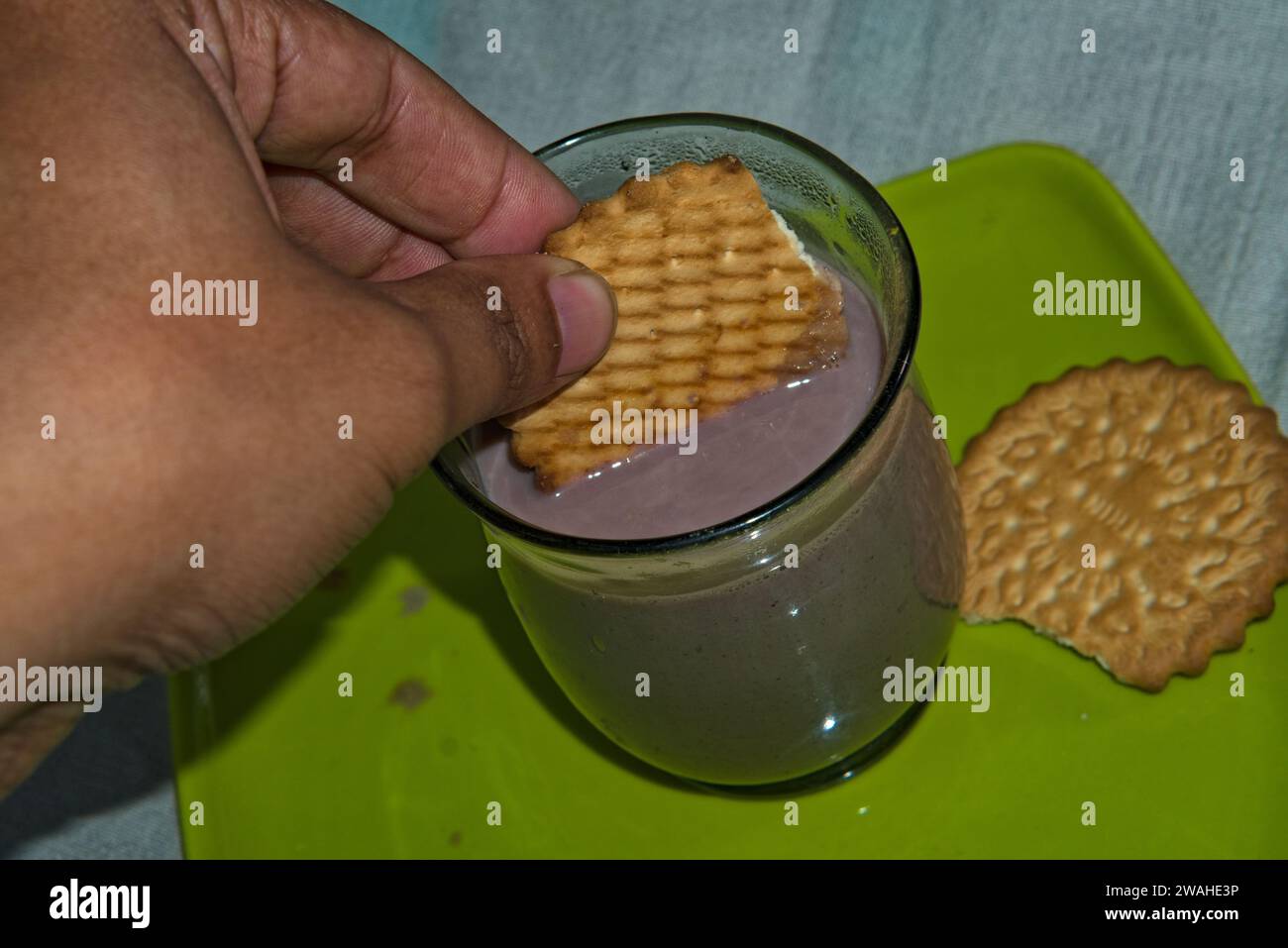 dipping a round shaped biscuit in chocolate milk Stock Photo