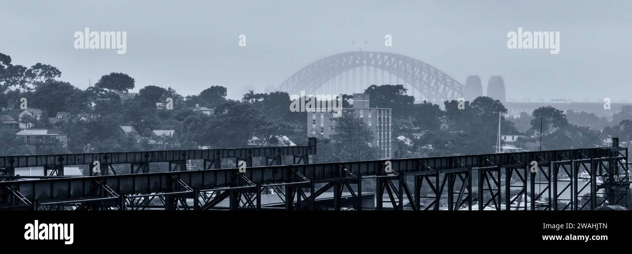 The Sydney Harbuor Bridge in the fog with the White Bay Cruise Terminal in the foreground Stock Photo