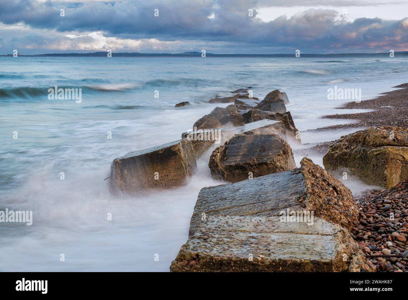 Weathered Anti-Tank Concrete Blocks in the windy sea. Findhorn Beach, Morayshire, Scotland. Long exposure Stock Photo