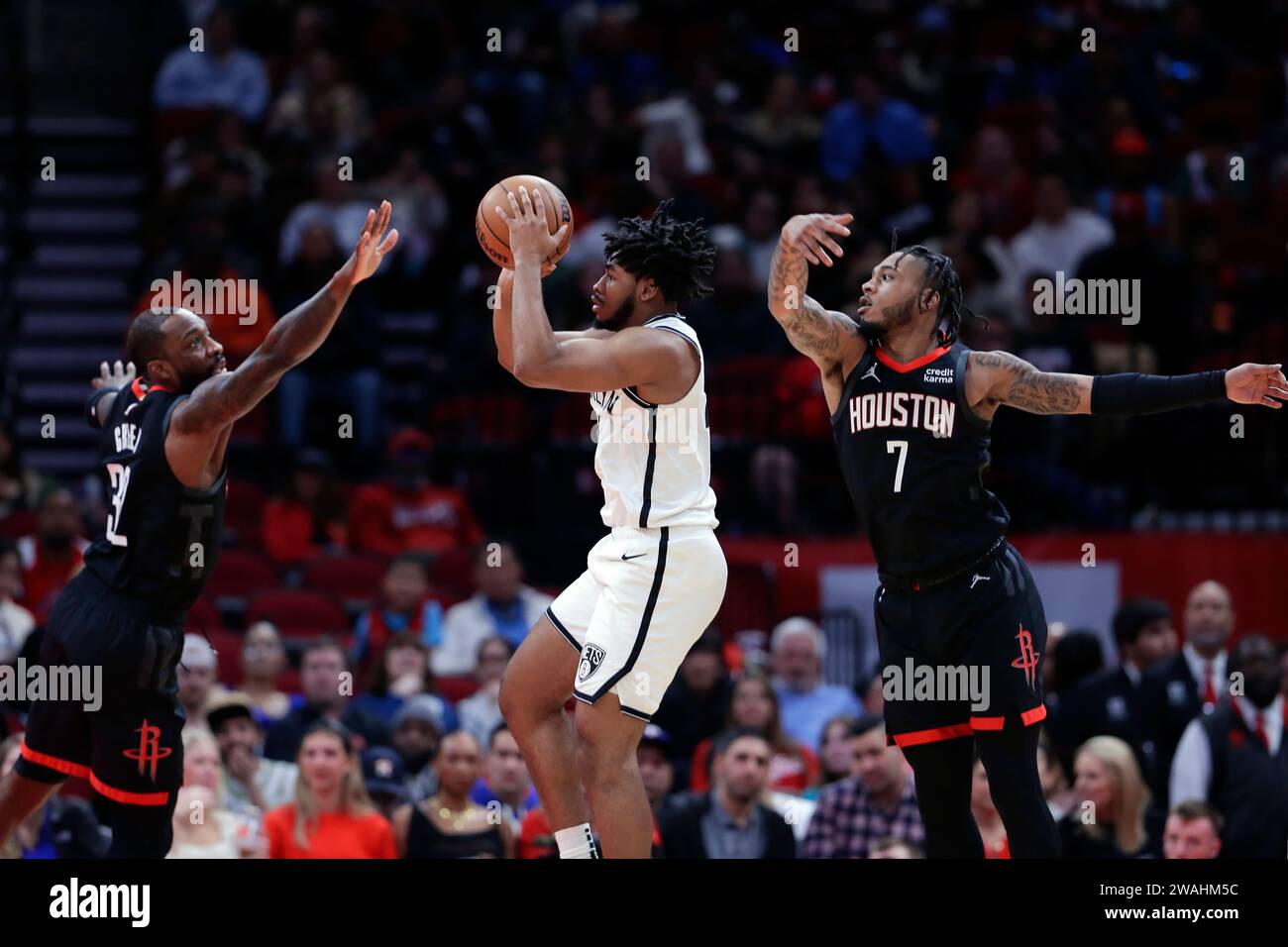 Brooklyn Nets guard Cam Thomas, center, jumps up to pass the ball between Houston Rockets