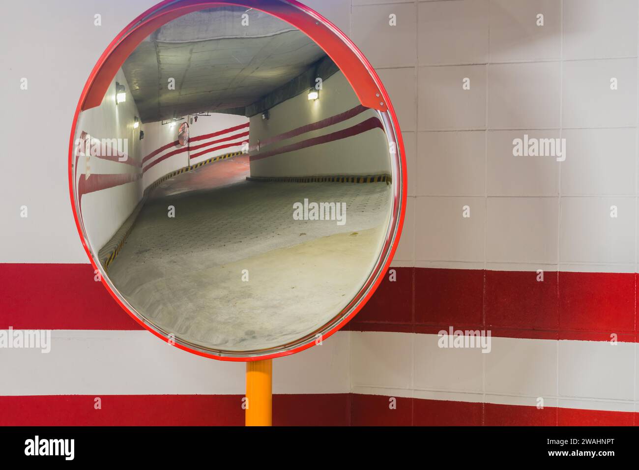 Closeup of large round parking garage mirror with reflection of ramp to