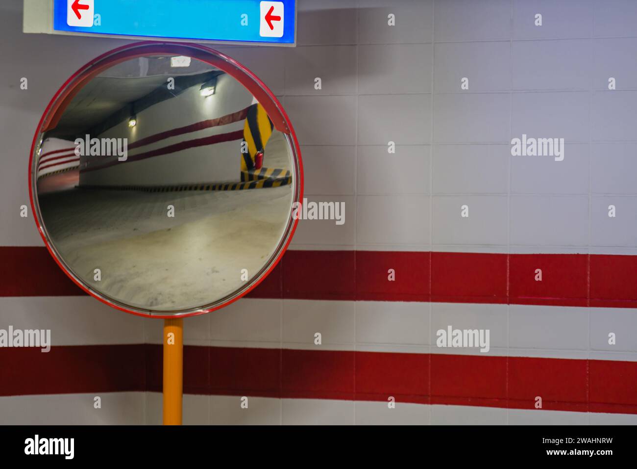 Closeup of large round parking garage mirror with reflection of ramp to