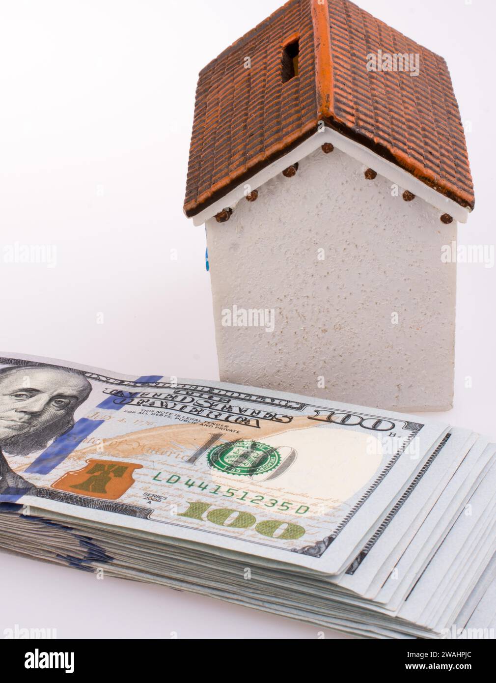 American dollar banknotes on the roof of a model house on white background Stock Photo