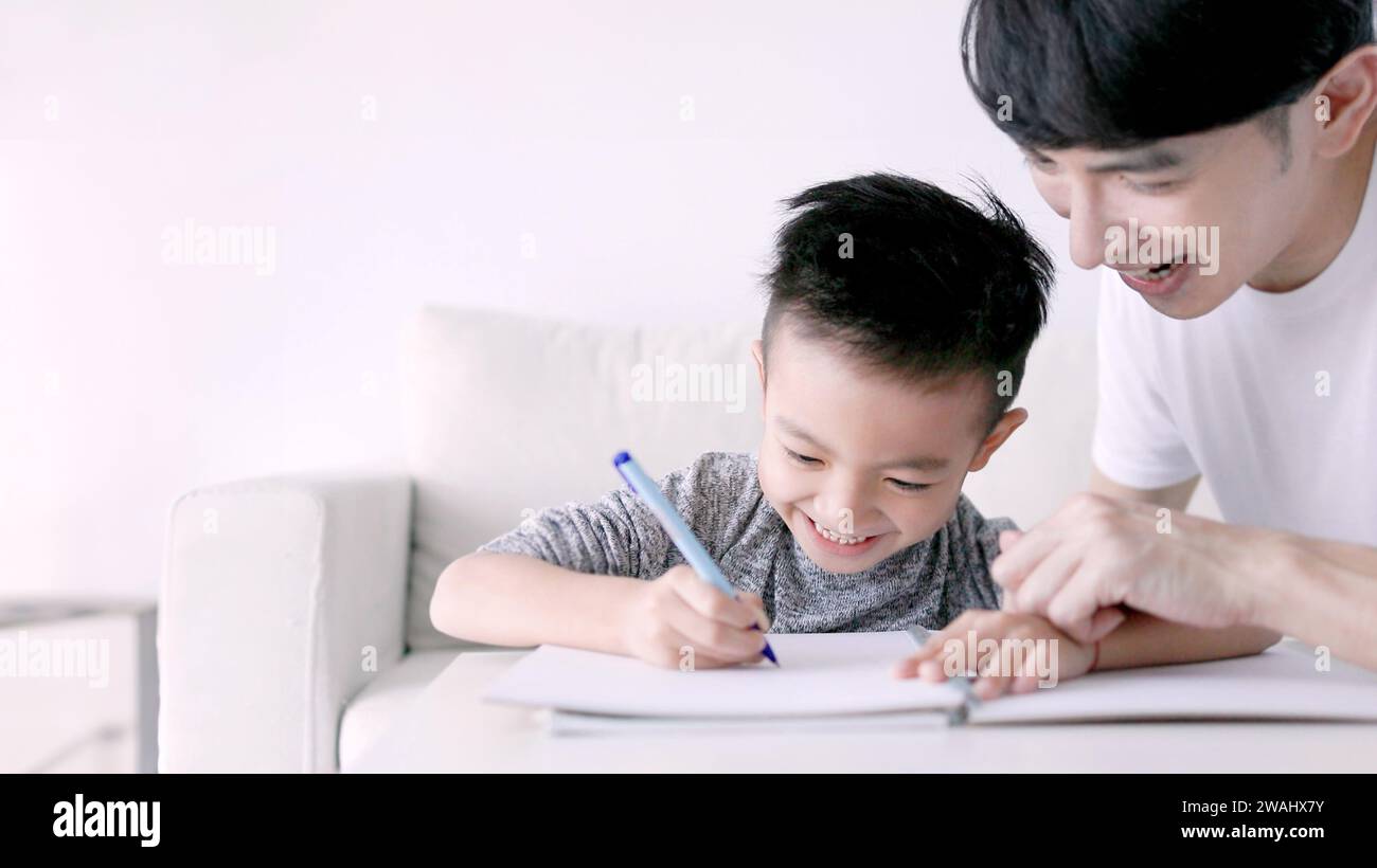 Young father checking homework helping  child  with study at home Stock Photo