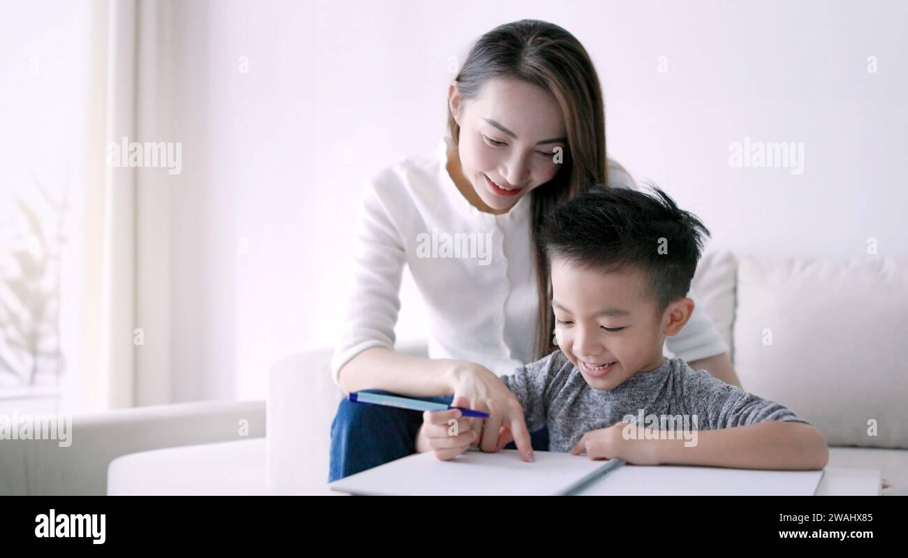 Young mother checking homework helping  child  with study at home Stock Photo