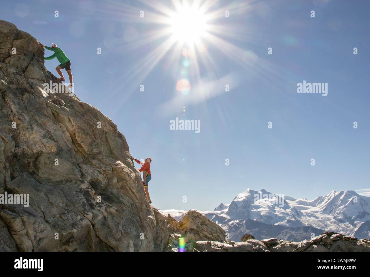 Monochrome image of two climber on a rugged mountain under a radiant sunburst Stock Photo