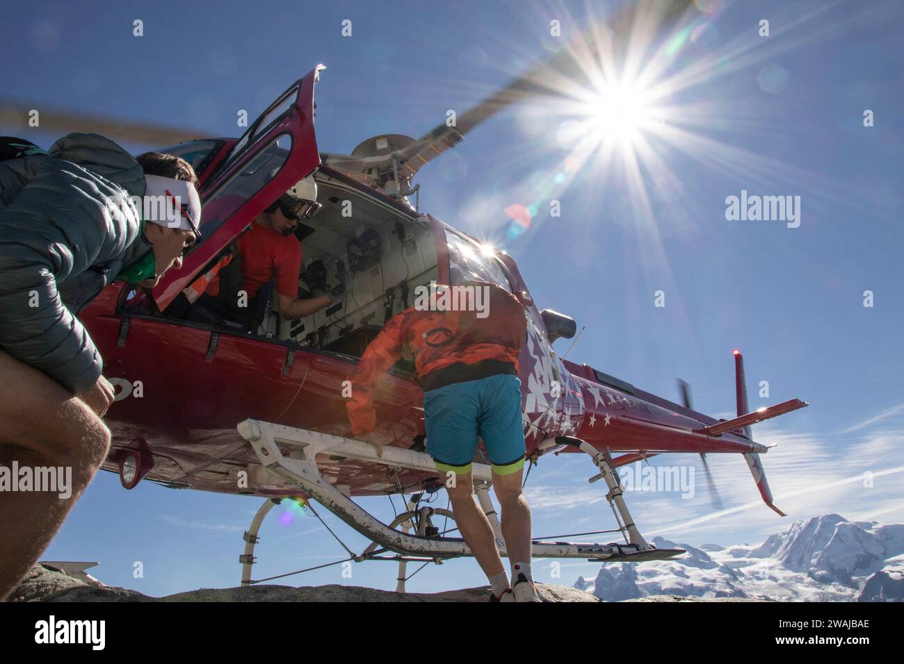 From below of skiers boarding a rescue helicopter on a bright sunny day in the high mountains Stock Photo