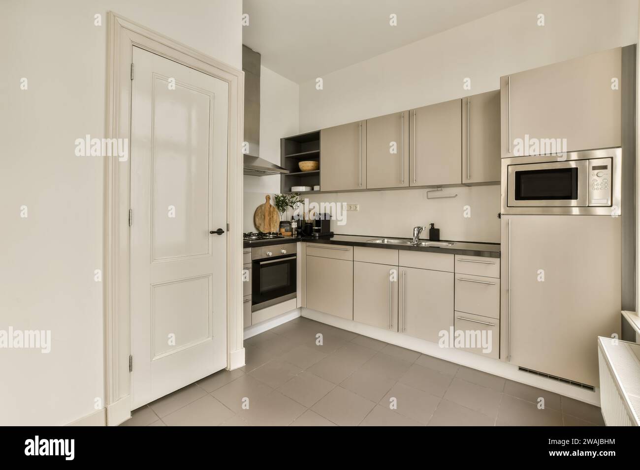 Interior of spacious kitchen with modern appliances and white cabinets at contemporary apartment Stock Photo