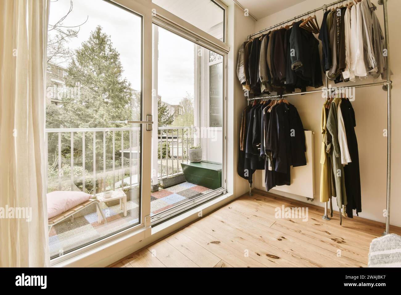 Various clothes hanging on rack by large bright window overlooking ...