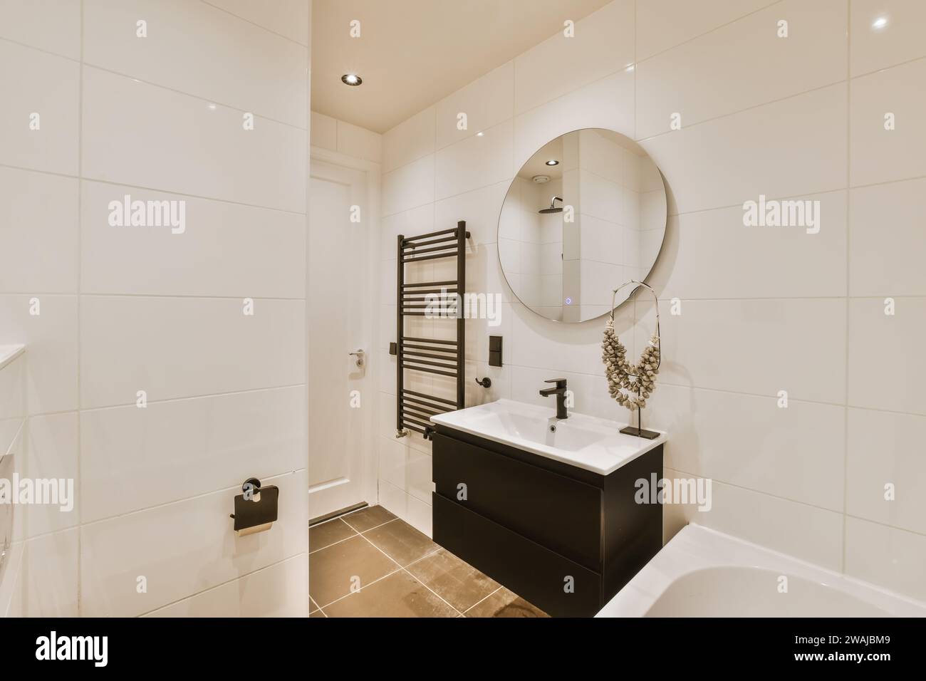 Round mirror over sink and black mounted on tiled wall in
