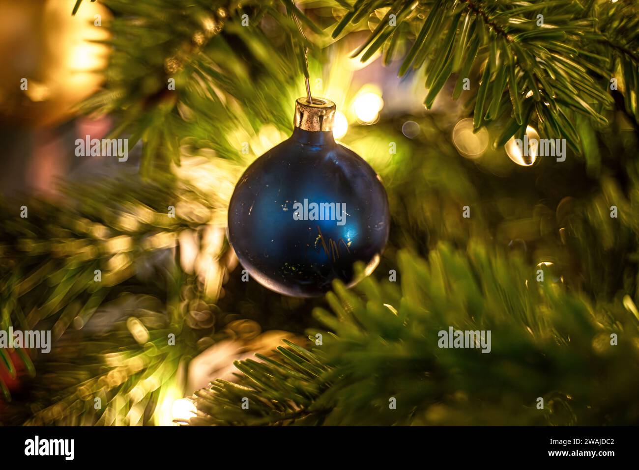 A festive blue Christmas ornament with illuminated lights in the background, creates a warm atmosphere Stock Photo