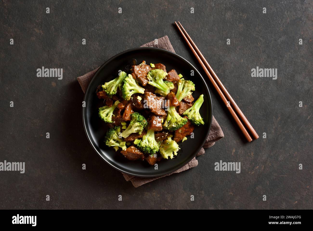 Beef with broccoli on plate over dark stone background with free space. Thinly sliced beef meat with roasted broccoli. Top view, flat lay Stock Photo