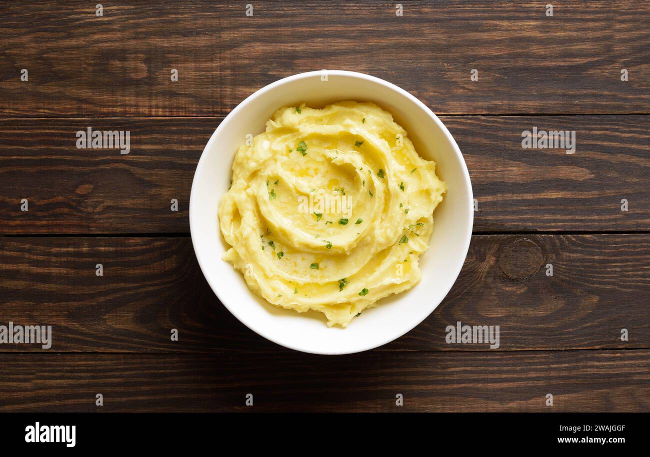 Mashed potatoes, boiled puree in bowl over wooden background with free space. Healthy comfort food. Top view, flat lay Stock Photo