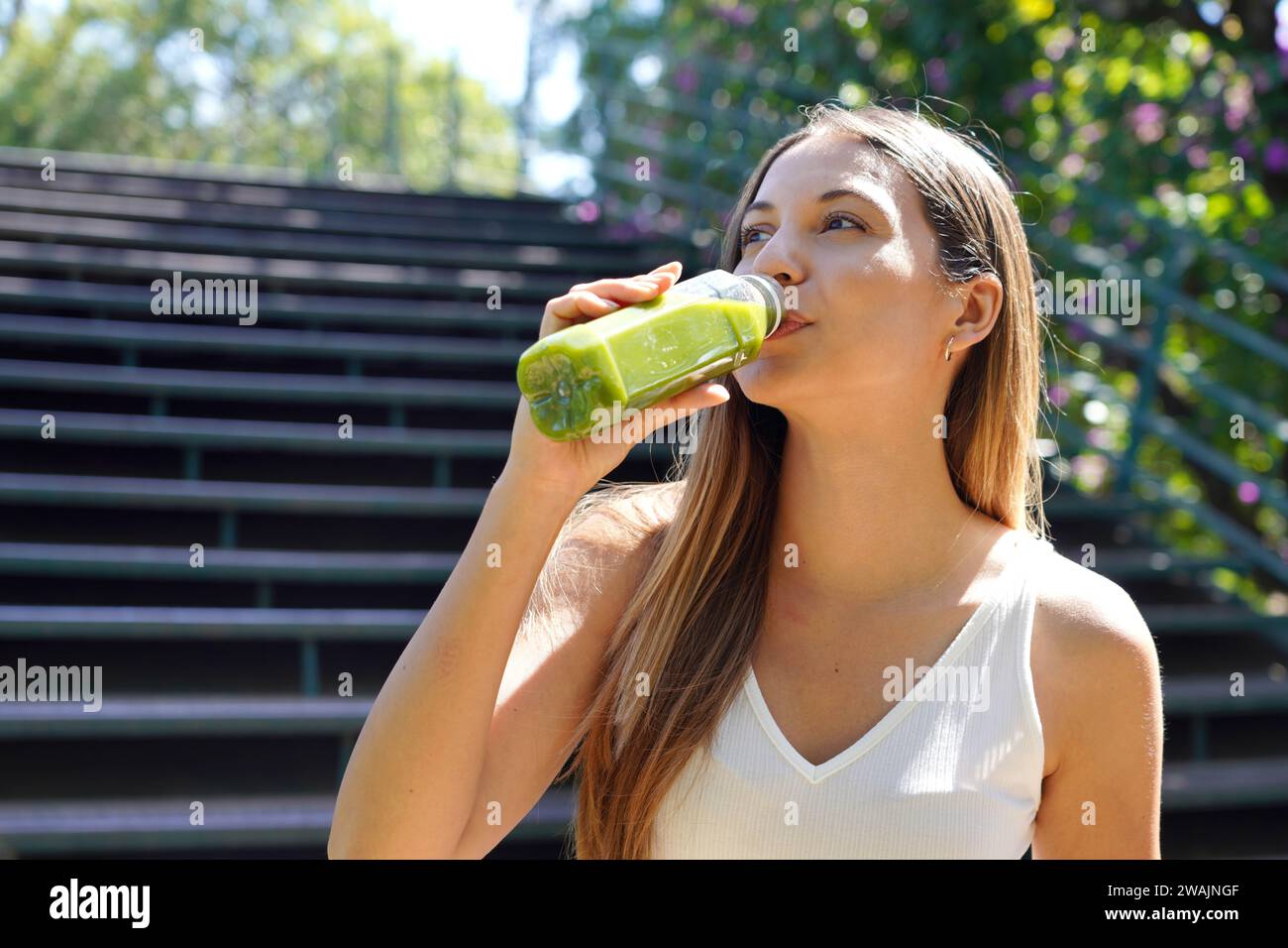 Beautiful healthy young woman drinking green smoothie detox juice outdoors Stock Photo