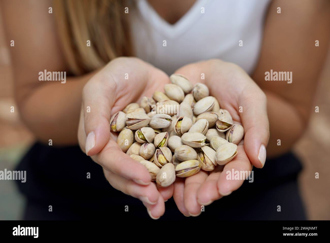 Pistachio seeds. Close-up of female hands holding pistachio seeds in the park. Stock Photo