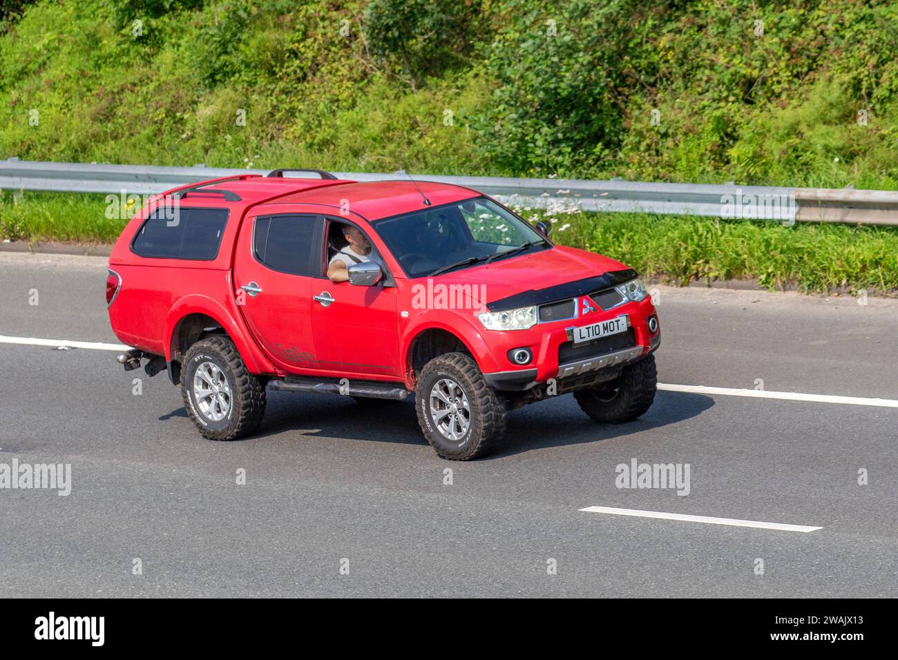 2010 Red Mitsubishi L200barb Lb Dcb Di-D4x4 A DI-D 178 Auto LCV Double Cab Pick Up Diesel work truck 2477 cc; travelling at speed on the M6 motorway in Greater Manchester, UK Stock Photo