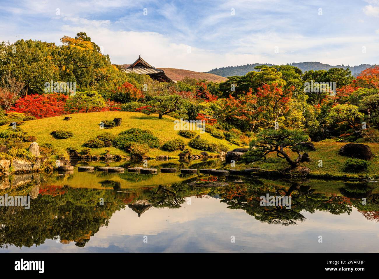 isuien gardens in nara in autumn reflections of colourful trees in the mirror lake with the borrowed scenery of mountains and nandaimon gate behind Stock Photo