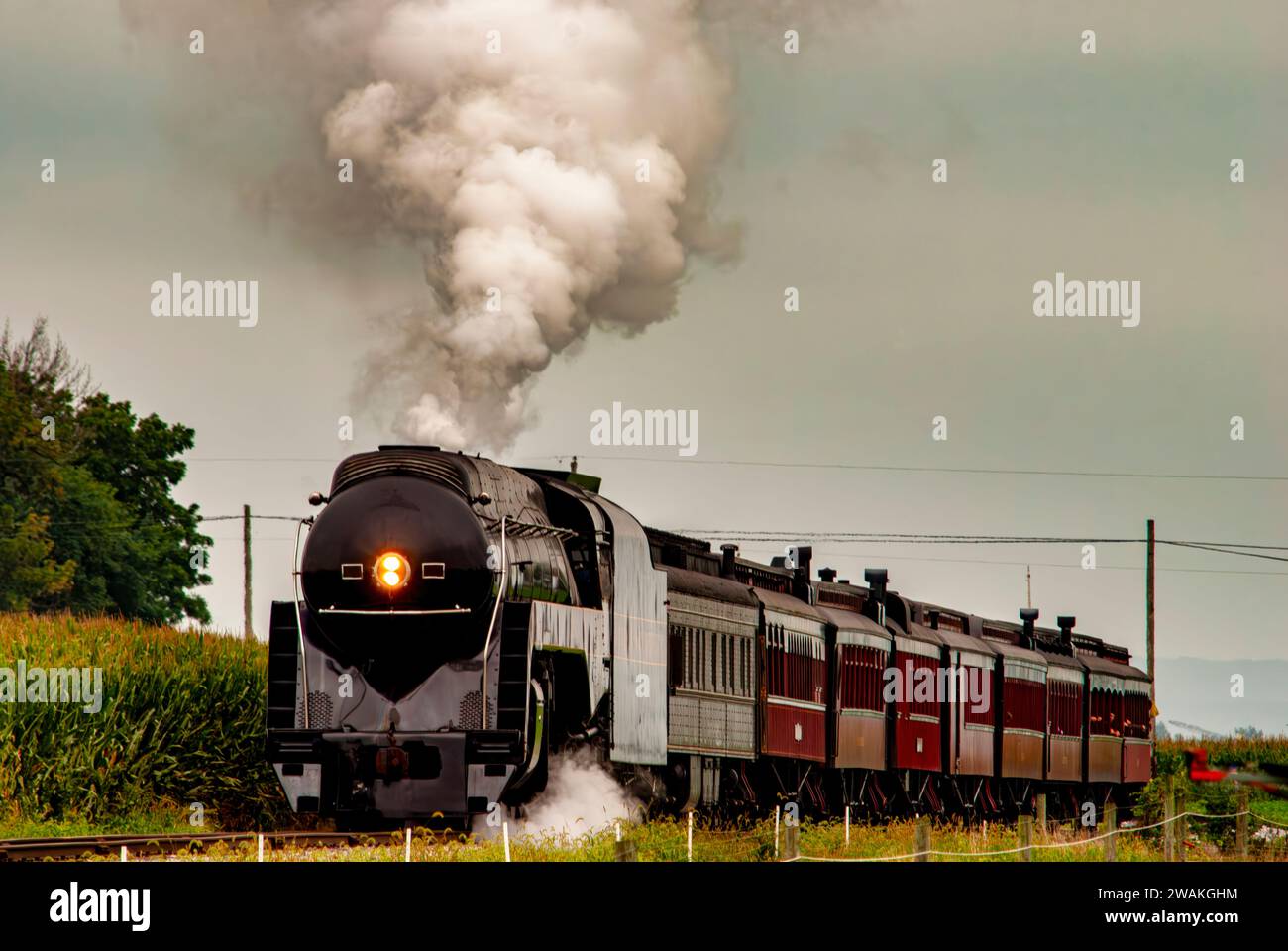 A vintage steam locomotive engine chugging along the railroad tracks Stock Photo