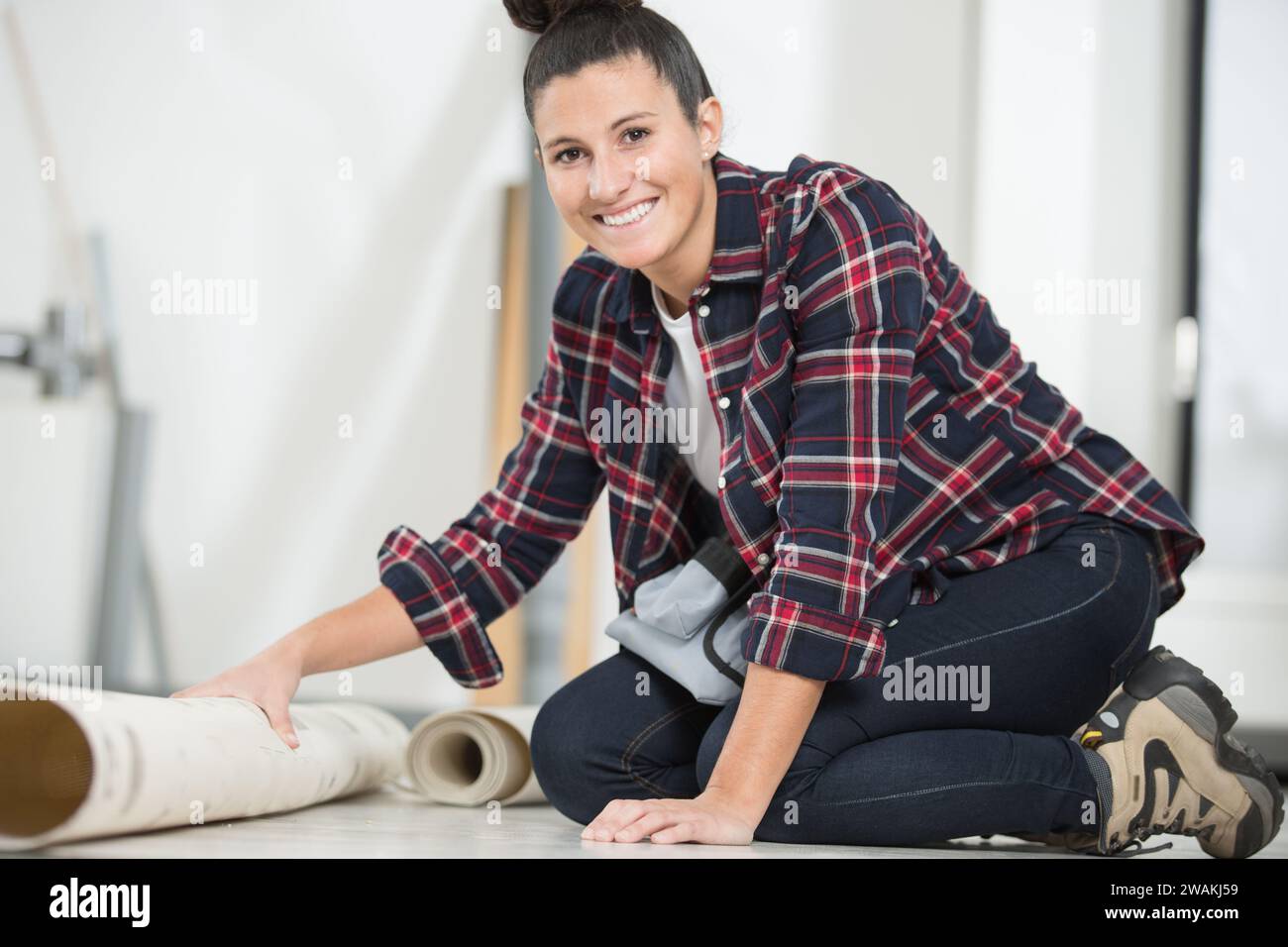 happy woman is unrolling a new carpet Stock Photo