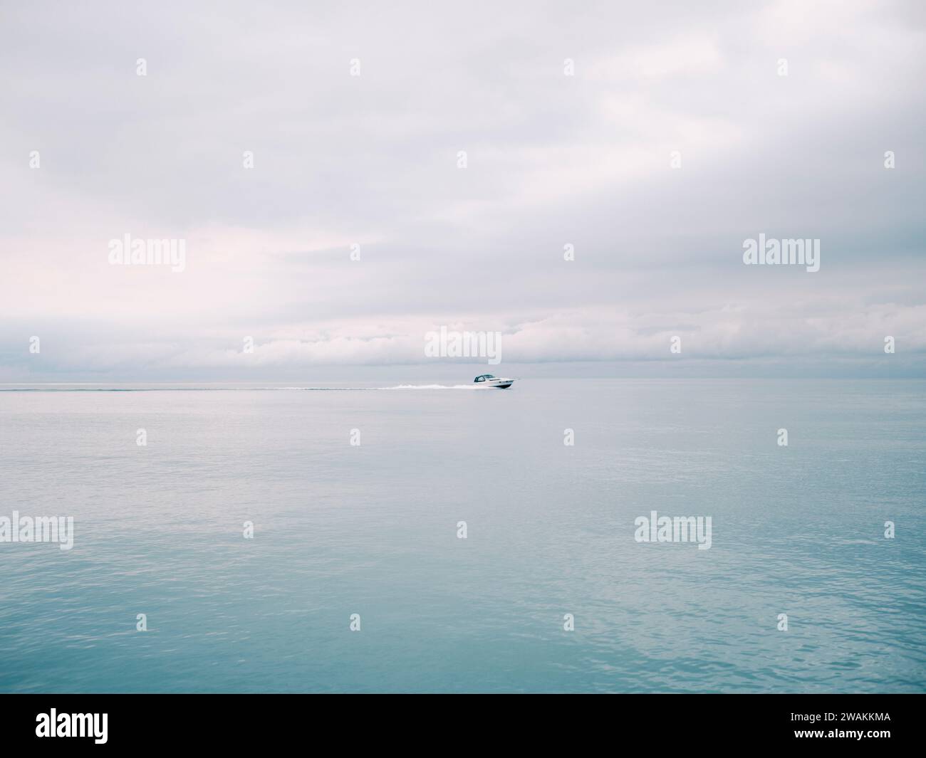 A small vessel sailing through choppy waters on a cloudy day, with no other vessels in sight. Stock Photo