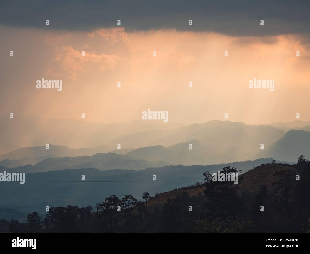 A dramatic sunset sky featuring a large rain cloud in the foreground. Stock Photo