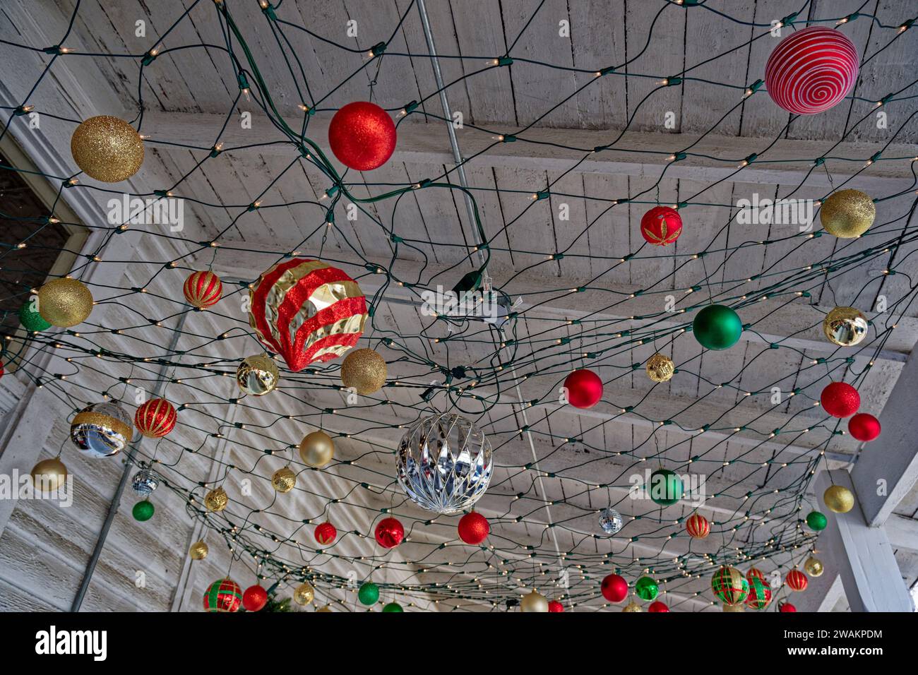 Variety of ornaments hanging from Christmas lights underneath the roof