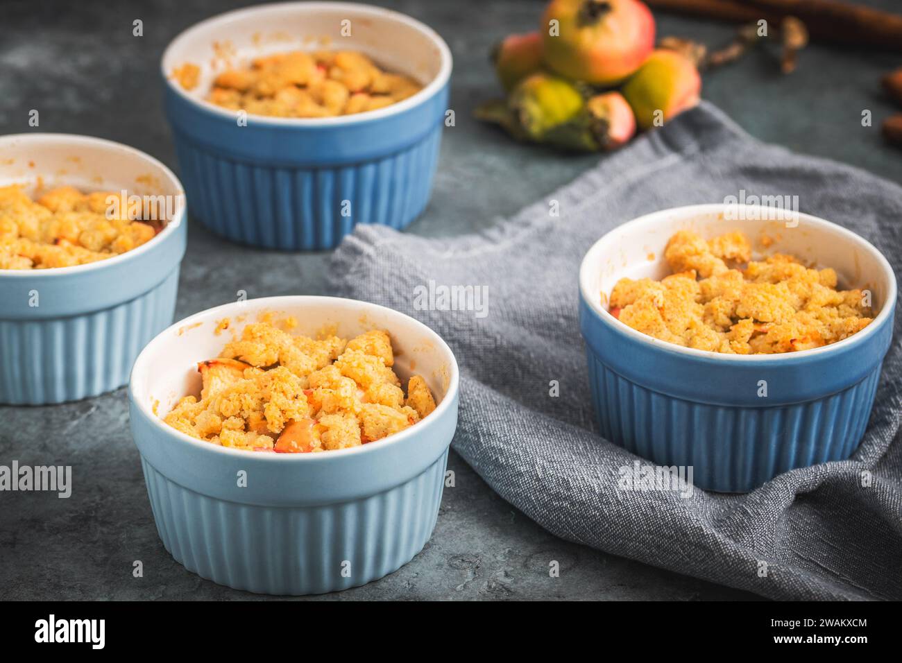 Apple crumble in small blue molds on a rustic gray table Stock Photo